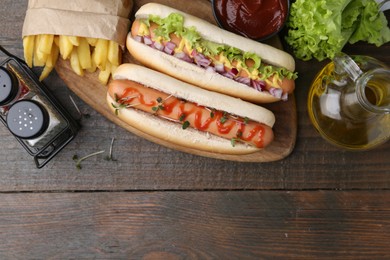 Photo of Tasty hot dogs served on wooden table, flat lay. Space for text