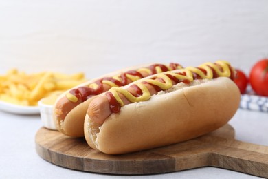 Photo of Tasty hot dogs served on light table, closeup