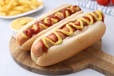 Photo of Tasty hot dogs served on light table, closeup