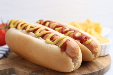 Photo of Tasty hot dogs served on light table, closeup