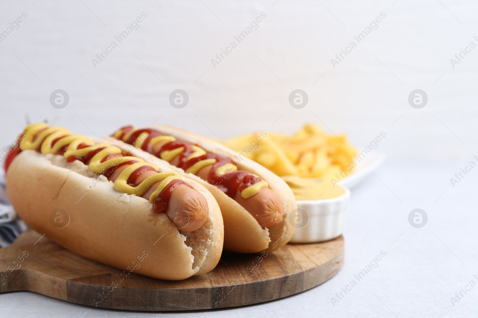 Photo of Tasty hot dogs served on light table, closeup. Space for text