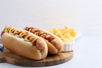 Photo of Tasty hot dogs served on light table, closeup. Space for text