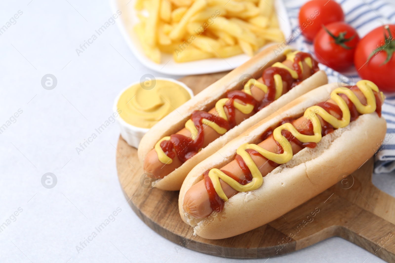 Photo of Tasty hot dogs served on light table, closeup