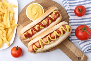 Photo of Tasty hot dogs served on light table, flat lay