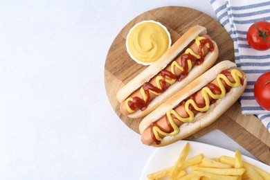 Photo of Tasty hot dogs served on light table, flat lay. Space for text