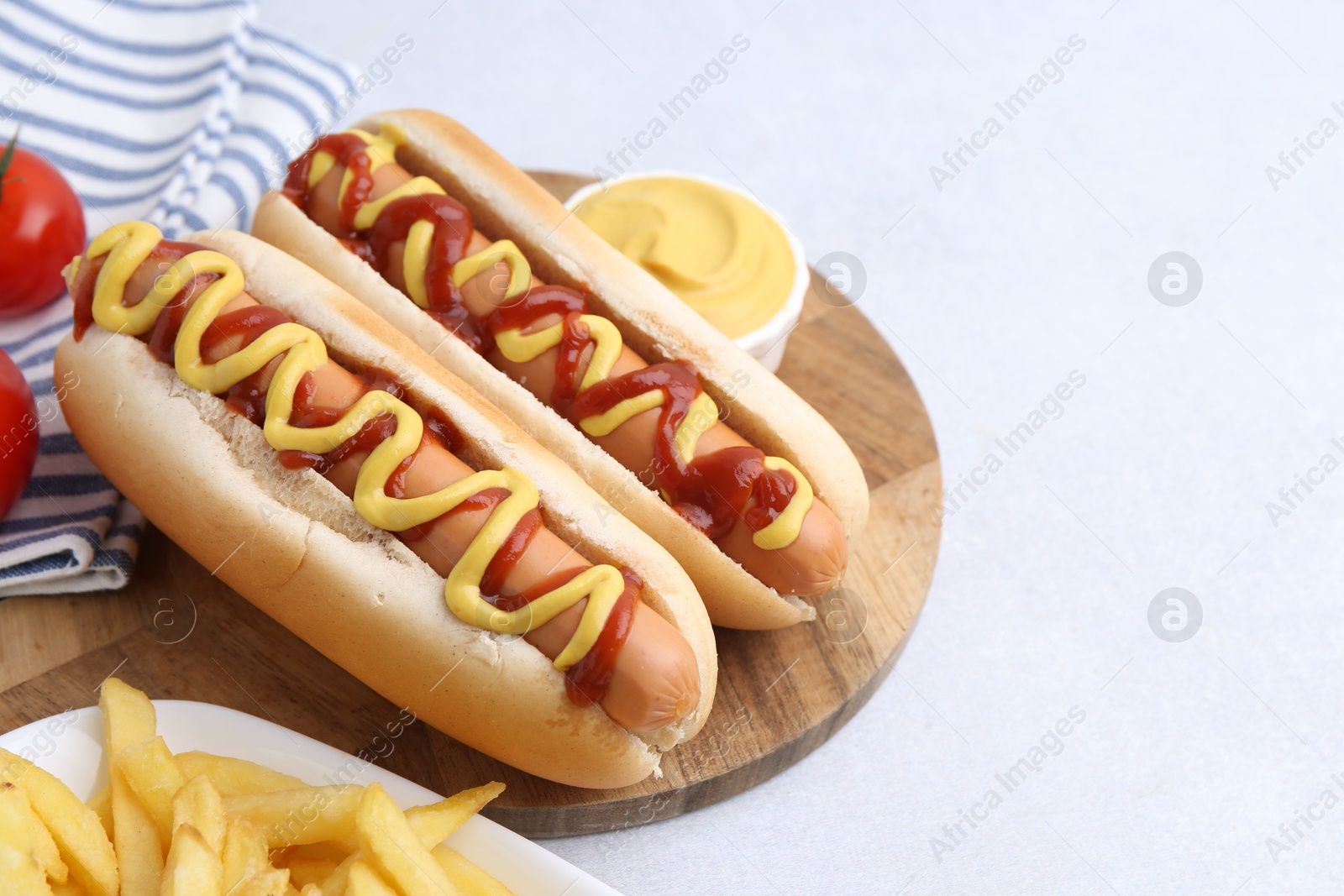 Photo of Tasty hot dogs served on light table, closeup. Space for text