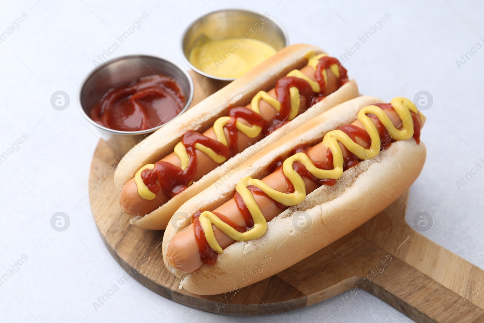 Photo of Tasty hot dogs with ketchup and mustard on light table, closeup