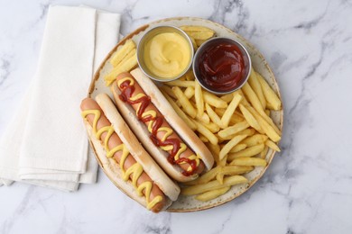 Photo of Tasty hot dogs with fries served on white marble table, top view