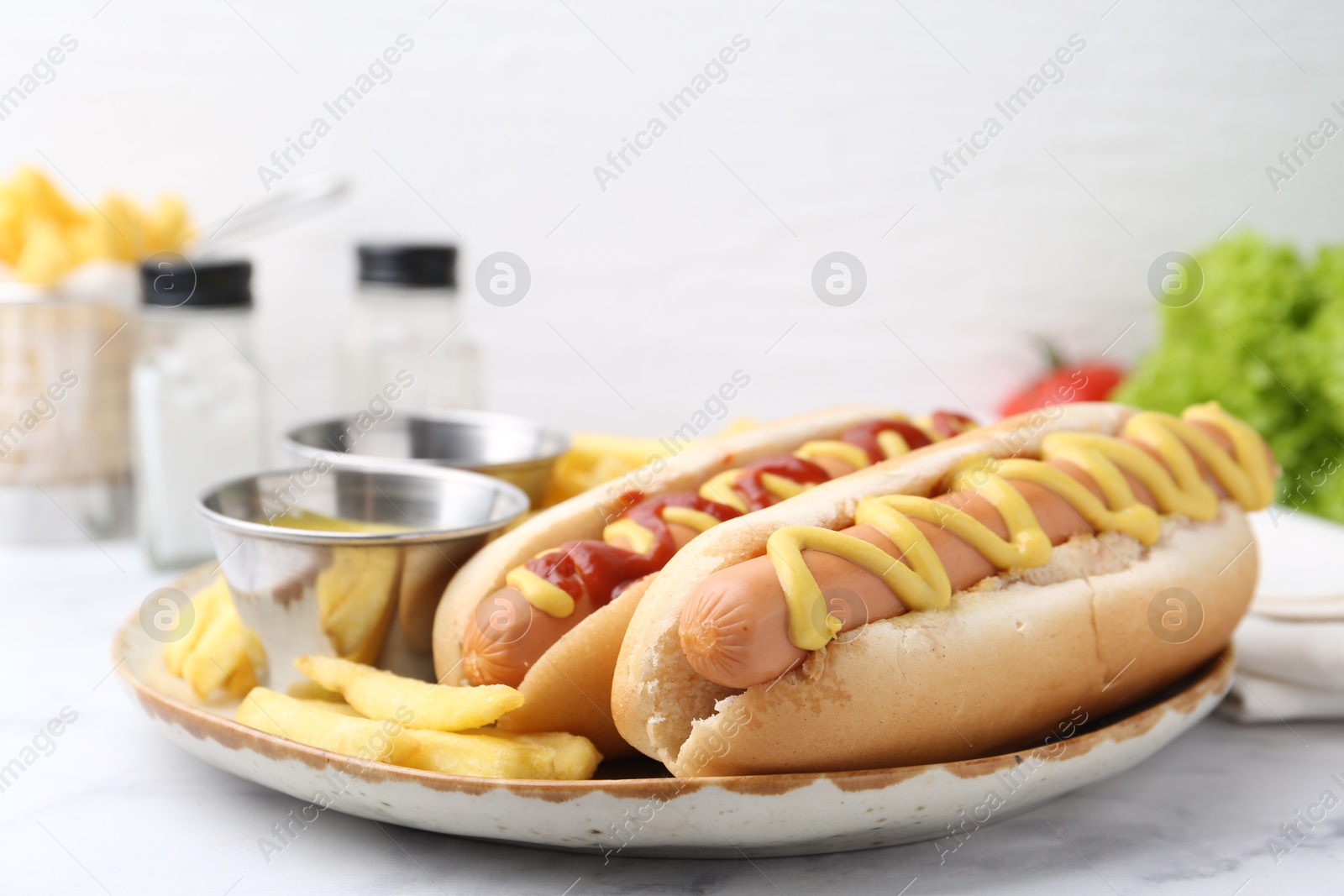 Photo of Tasty hot dogs with fries served on white marble table, closeup