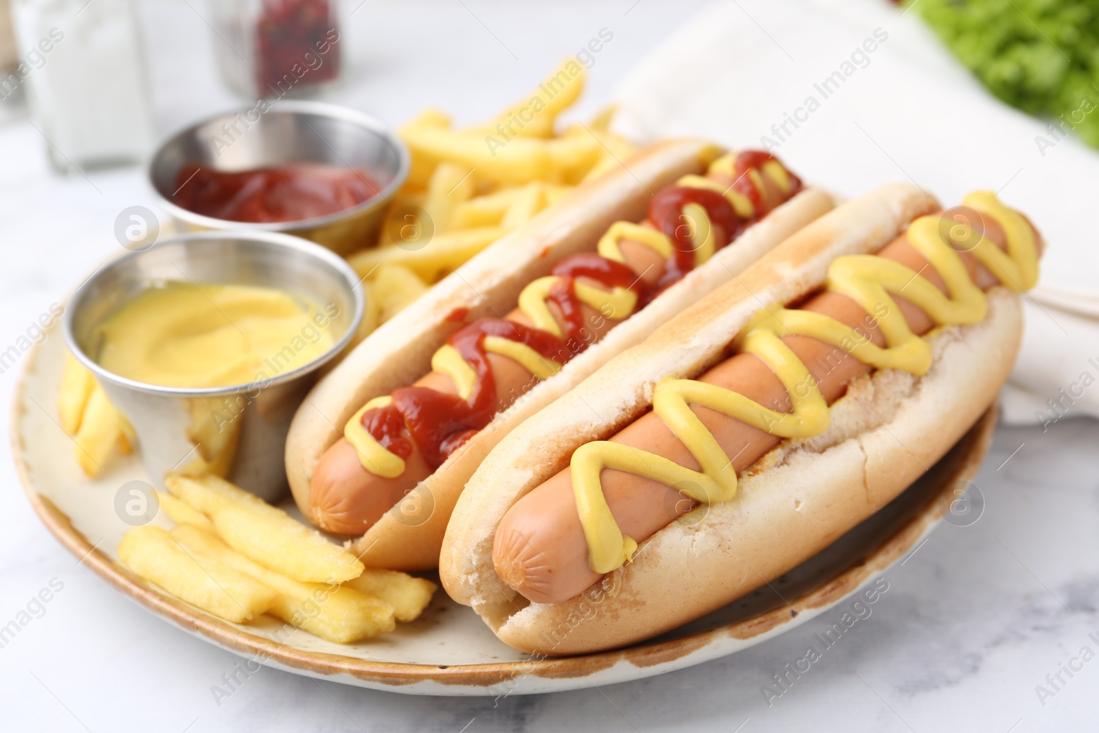 Photo of Tasty hot dogs with fries served on white marble table, closeup