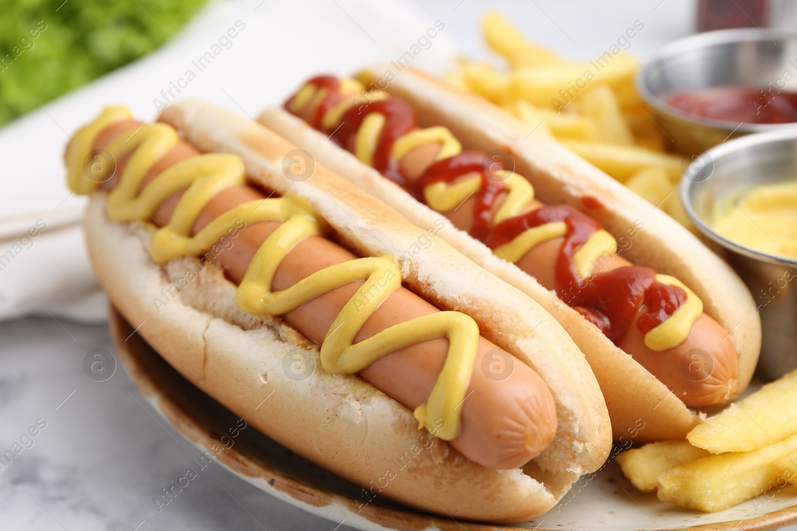 Photo of Tasty hot dogs with fries on white marble table, closeup