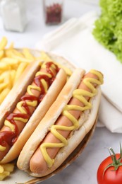 Photo of Tasty hot dogs with fries on white marble table, closeup