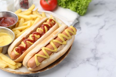 Photo of Tasty hot dogs with fries served on white marble table, closeup. Space for text