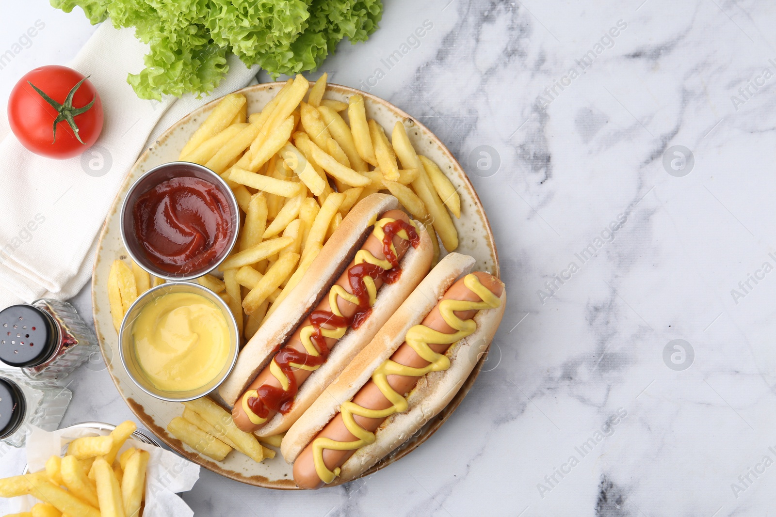 Photo of Tasty hot dogs with fries served on white marble table, flat lay. Space for text