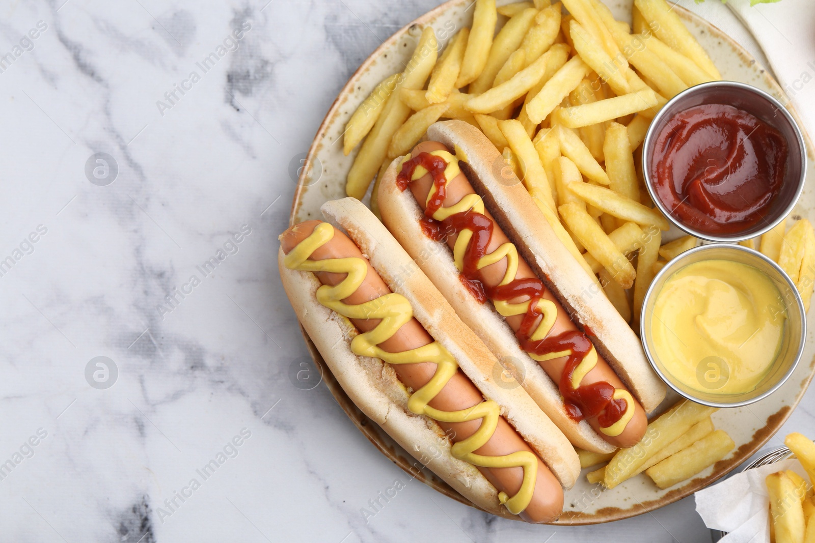 Photo of Tasty hot dogs with fries served on white marble table, top view. Space for text