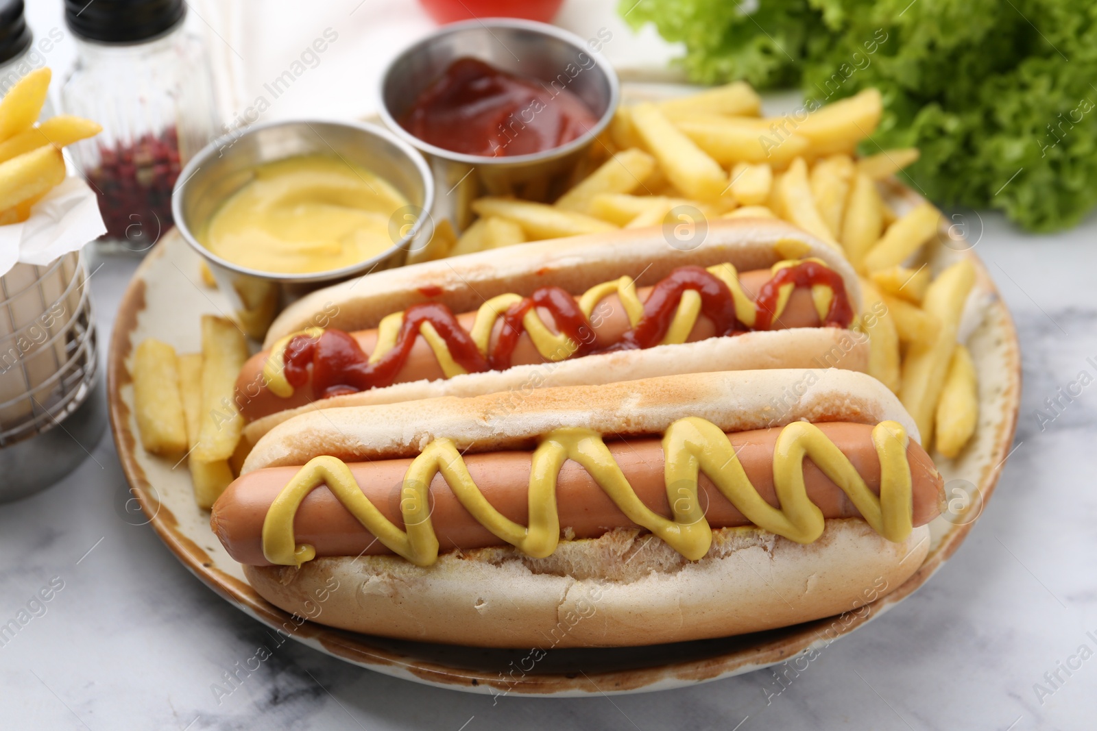 Photo of Tasty hot dogs with fries served on white marble table, closeup