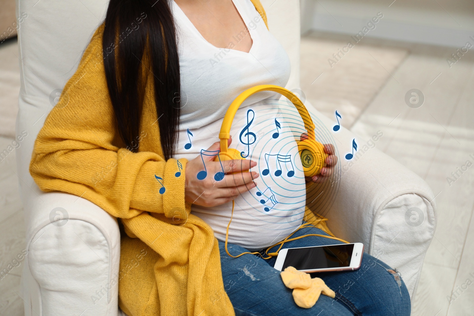 Image of Pregnant woman holding headphones near her belly at home, closeup. Music notes flying around