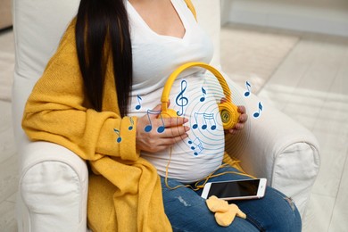 Image of Pregnant woman holding headphones near her belly at home, closeup. Music notes flying around