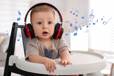 Image of Cute little baby with headphones on high chair at home. Music notes flying around