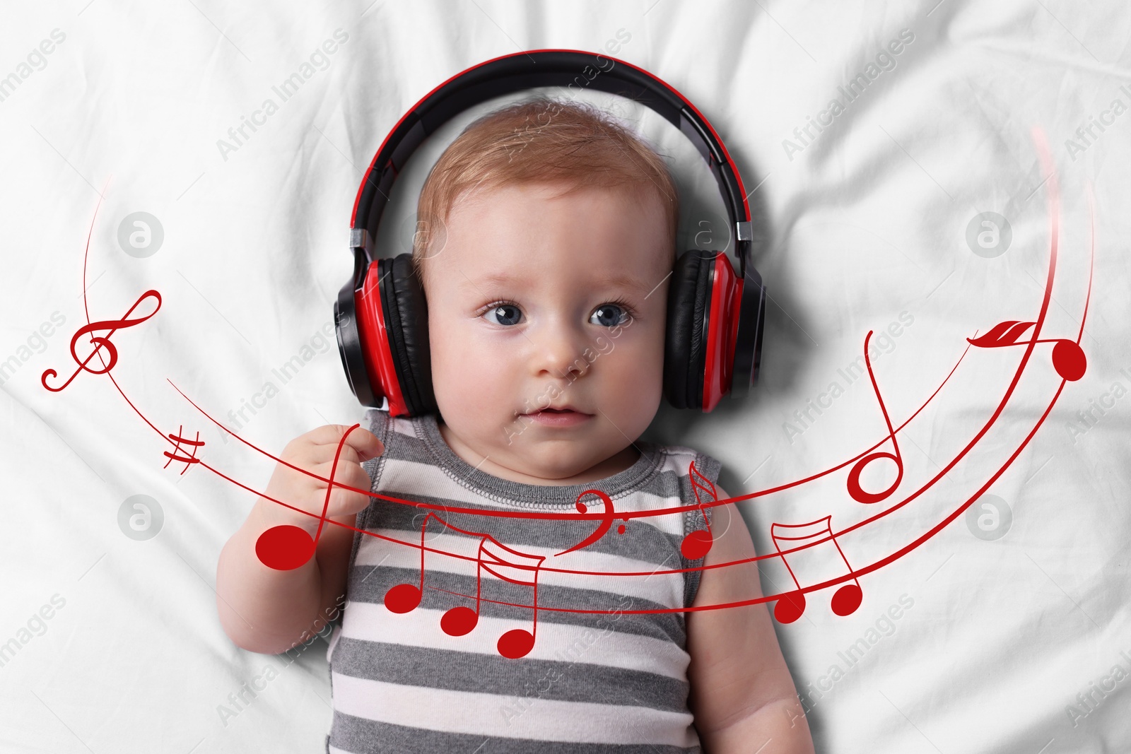 Image of Cute little baby with headphones lying on bed, top view. Music notes flying around