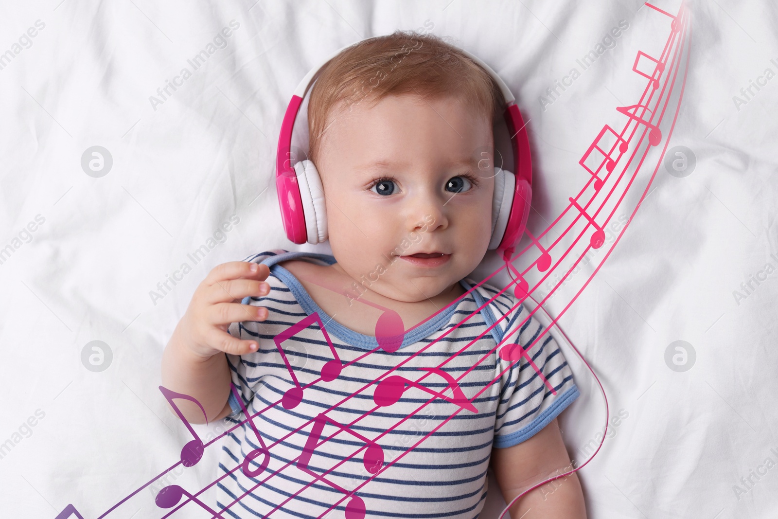 Image of Cute little baby with headphones lying on bed, top view. Music notes flying around