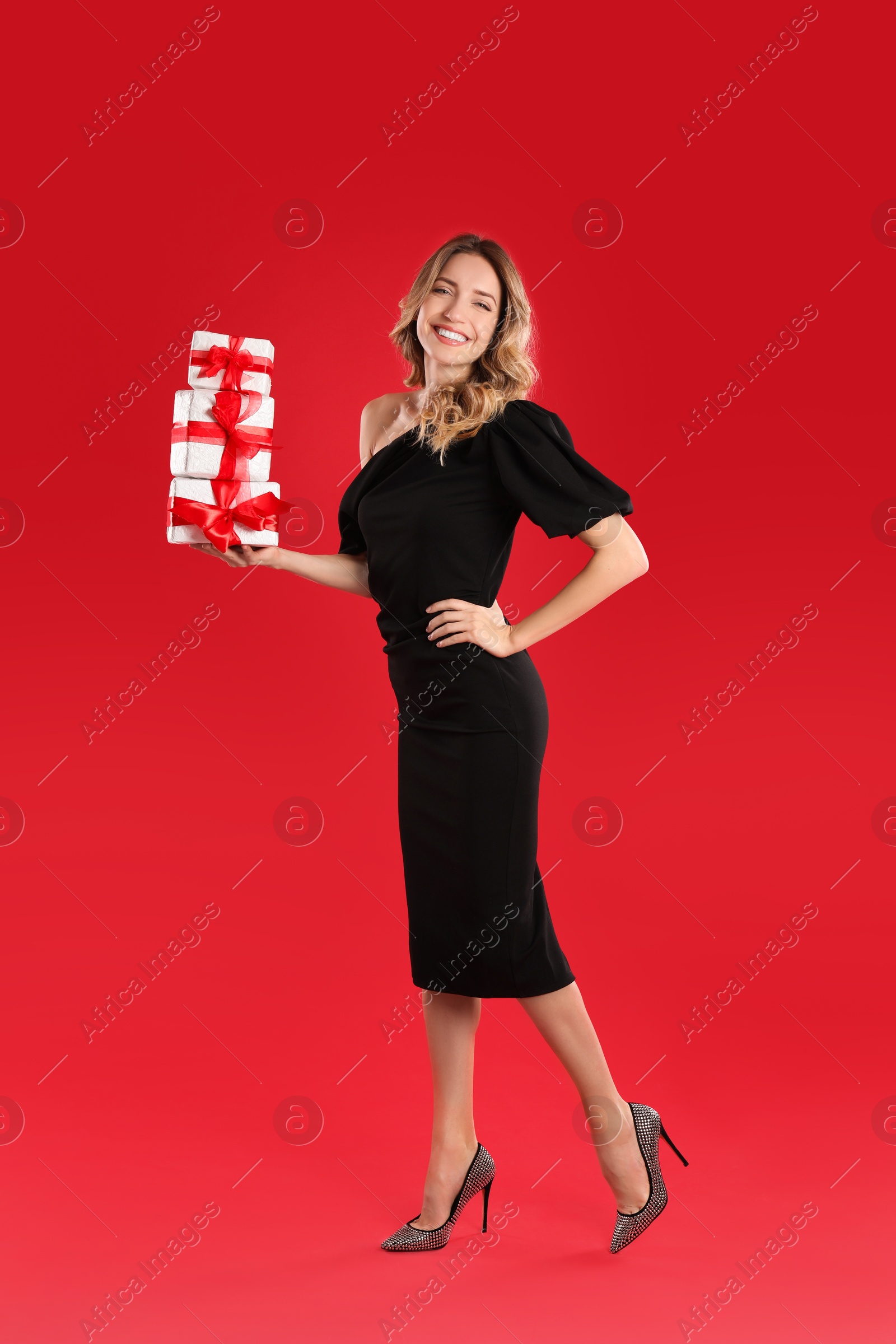 Photo of Beautiful young woman with Christmas presents on red background