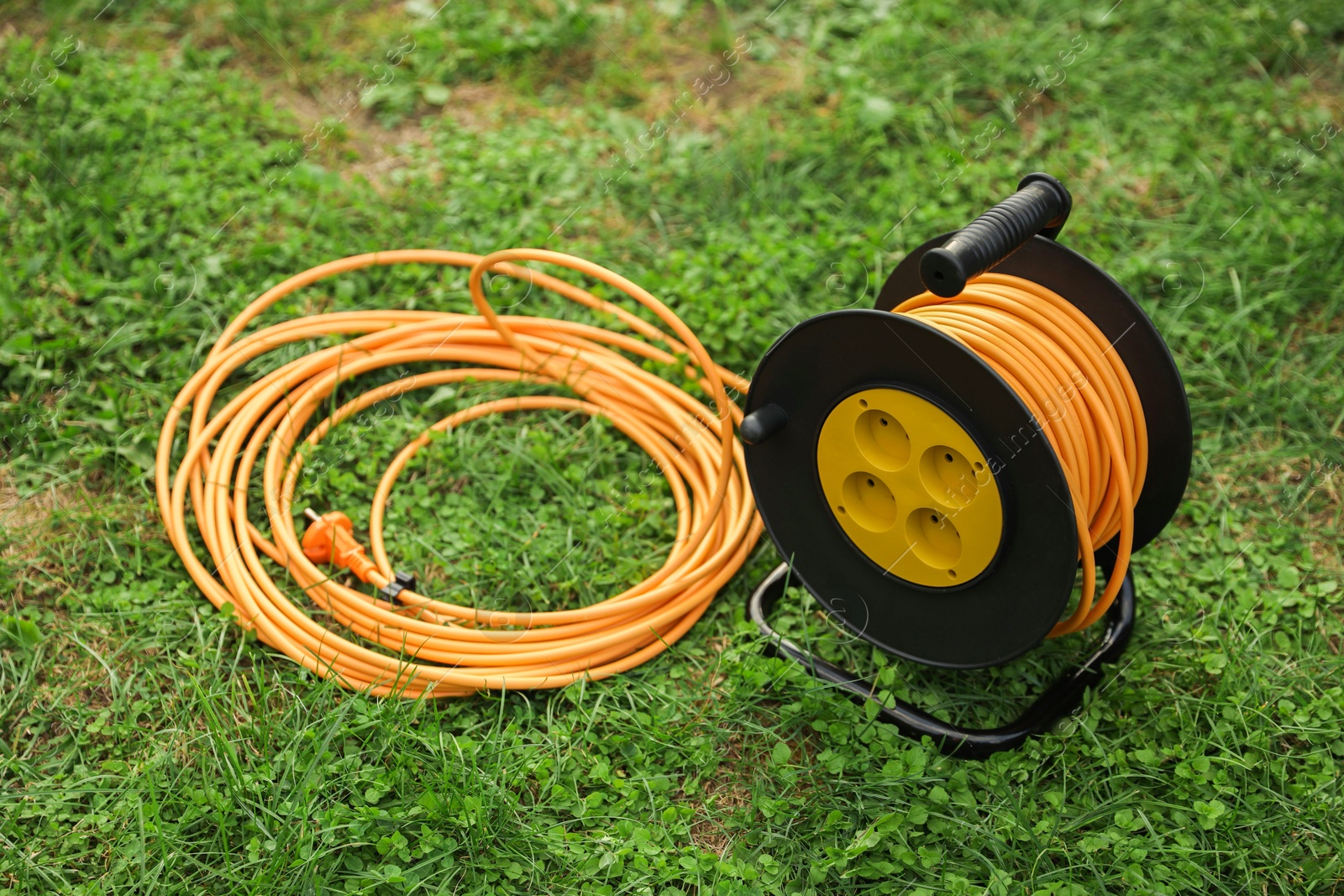 Photo of Extension cord reel on green grass outdoors