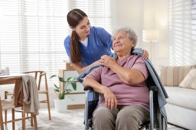 Photo of Caregiver covering senior woman with blanket indoors. Home health care service