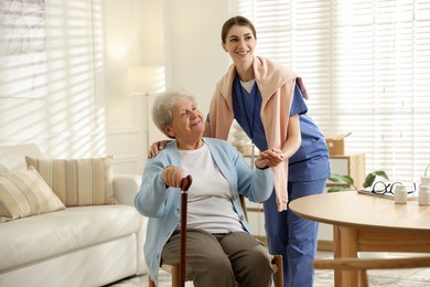 Caregiver supporting senior woman indoors. Home health care service