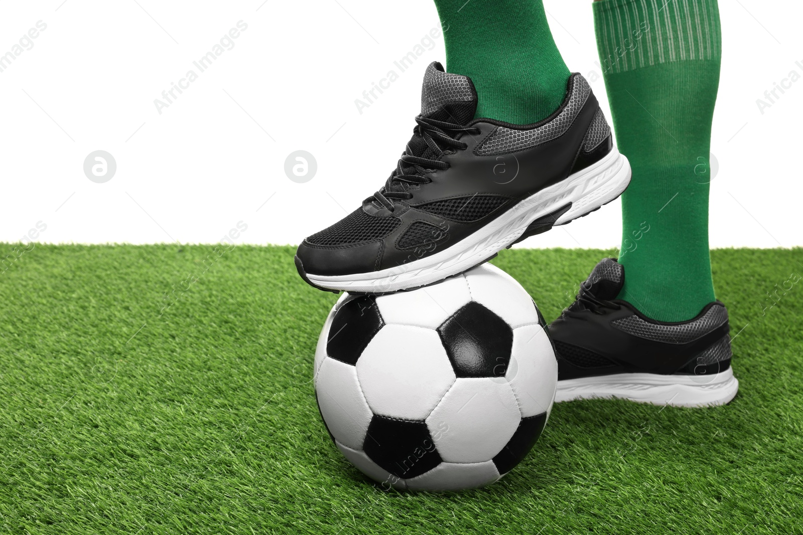 Photo of Football player with soccer ball on artificial grass against white background, closeup