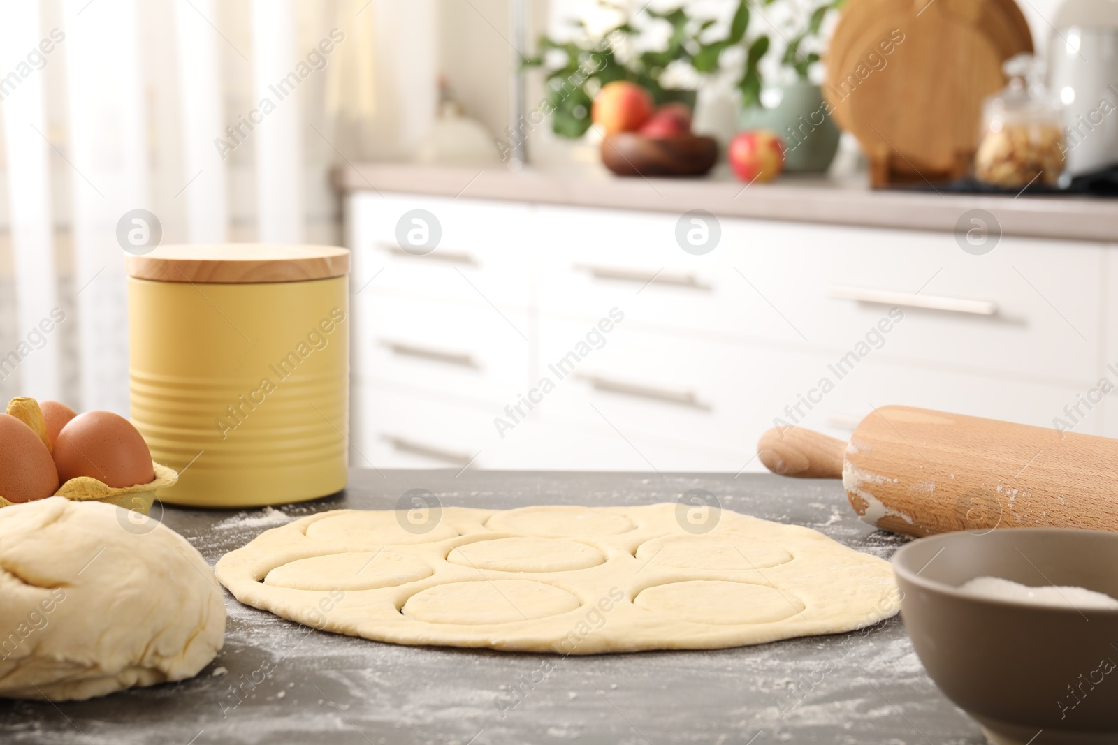 Photo of Making pirozhki (stuffed pastry pies). Raw dough, ingredients and rolling pin on gray table indoors