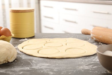 Photo of Making pirozhki (stuffed pastry pies). Raw dough, ingredients and rolling pin on gray table indoors