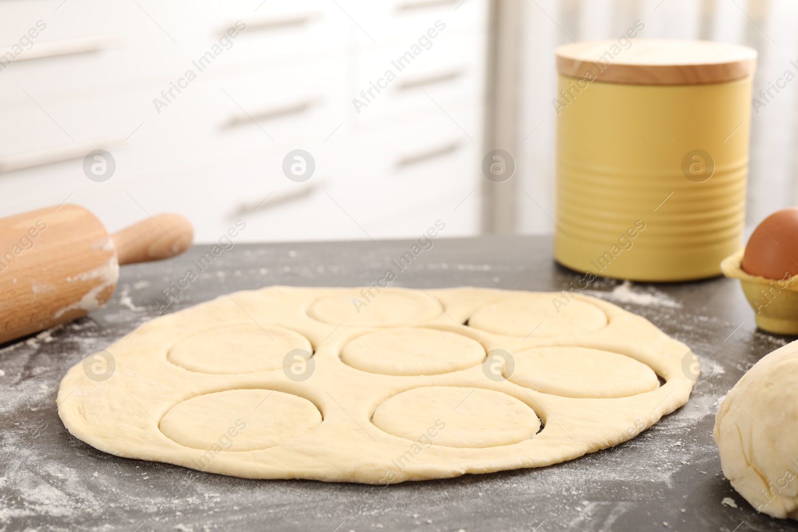 Photo of Making pirozhki (stuffed pastry pies). Raw dough and rolling pin on gray table indoors