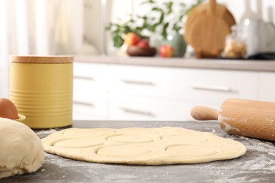 Photo of Making pirozhki (stuffed pastry pies). Raw dough and rolling pin on gray table indoors