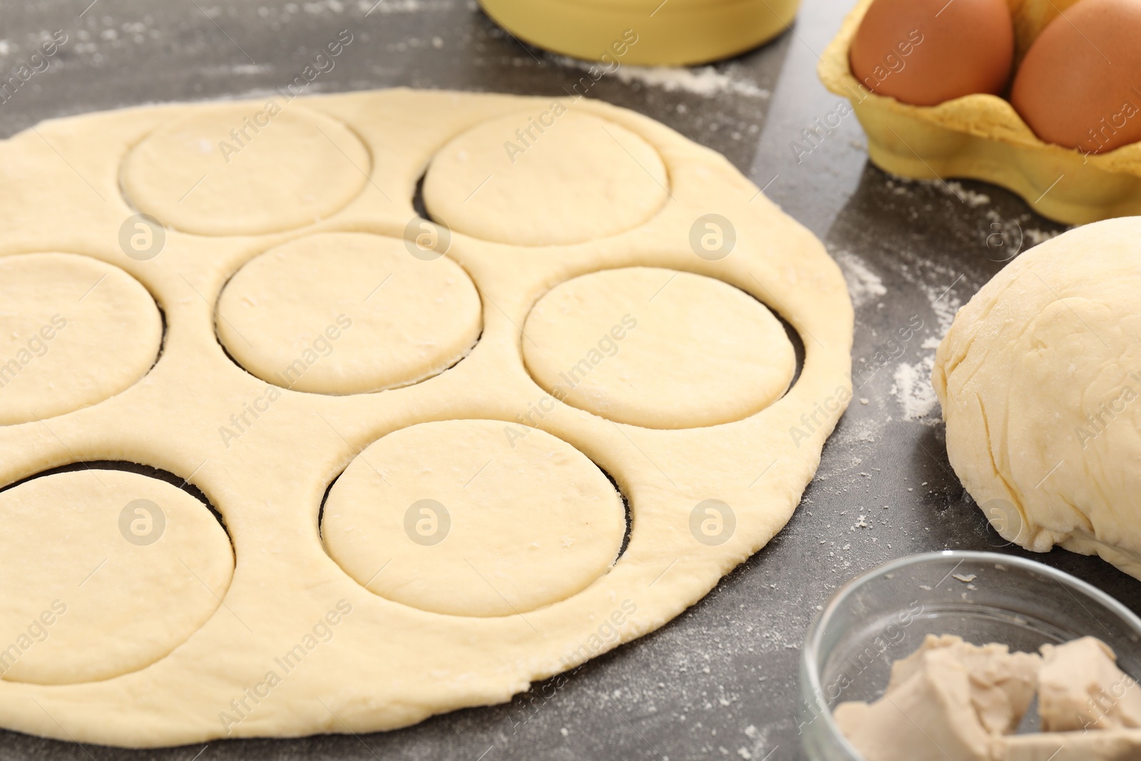 Photo of Making pirozhki (stuffed pastry pies). Raw dough and ingredients on gray table, closeup