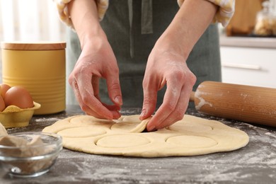 Photo of Woman making pirozhki (stuffed pastry pies) at gray table indoors, closeup