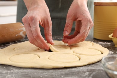 Photo of Woman making pirozhki (stuffed pastry pies) at gray table indoors, closeup