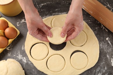 Photo of Woman making pirozhki (stuffed pastry pies) at gray table, above view