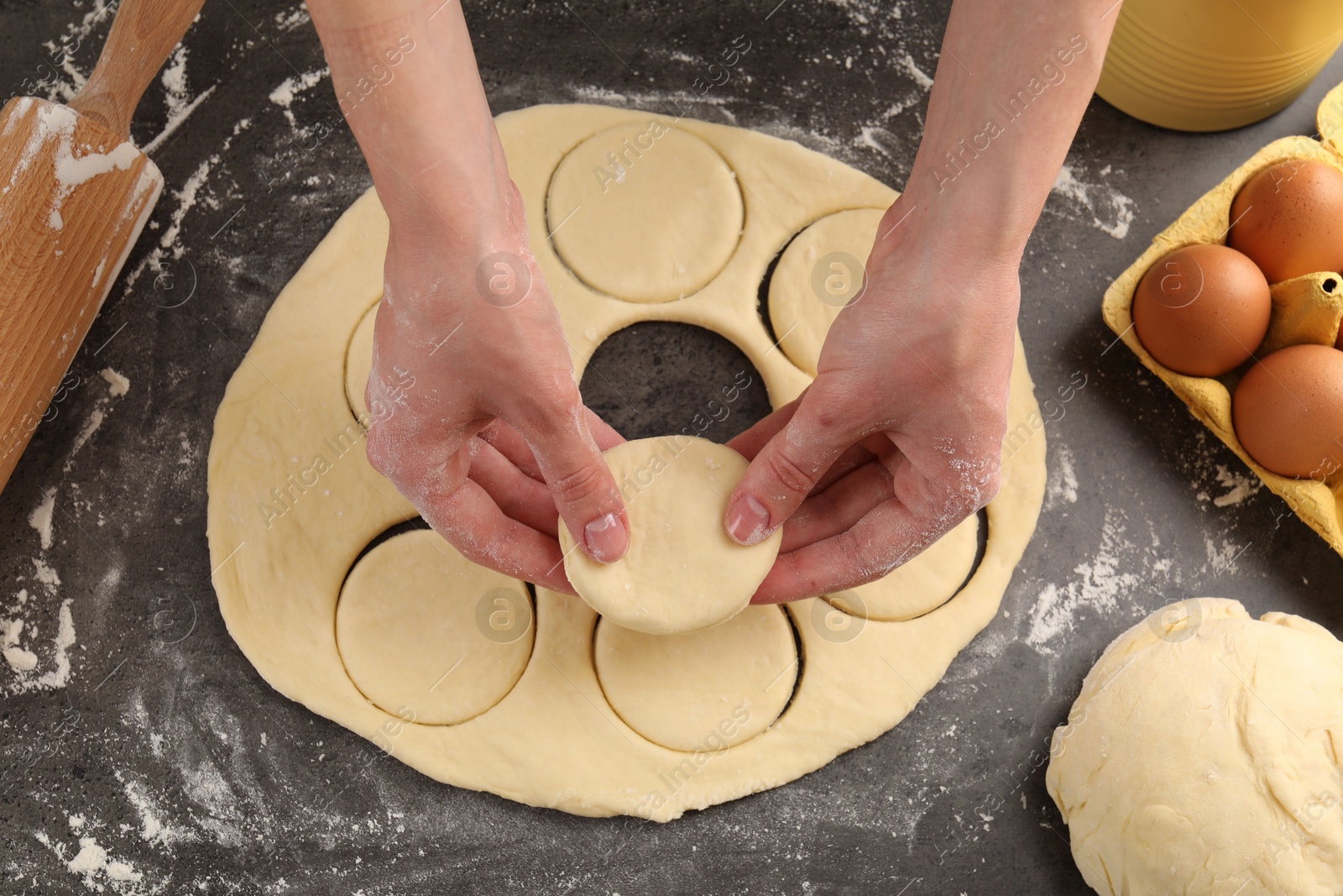 Photo of Woman making pirozhki (stuffed pastry pies) at gray table, top view