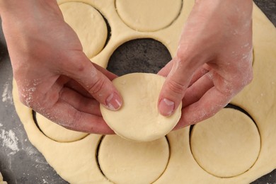 Photo of Woman making pirozhki (stuffed pastry pies) at gray table, top view