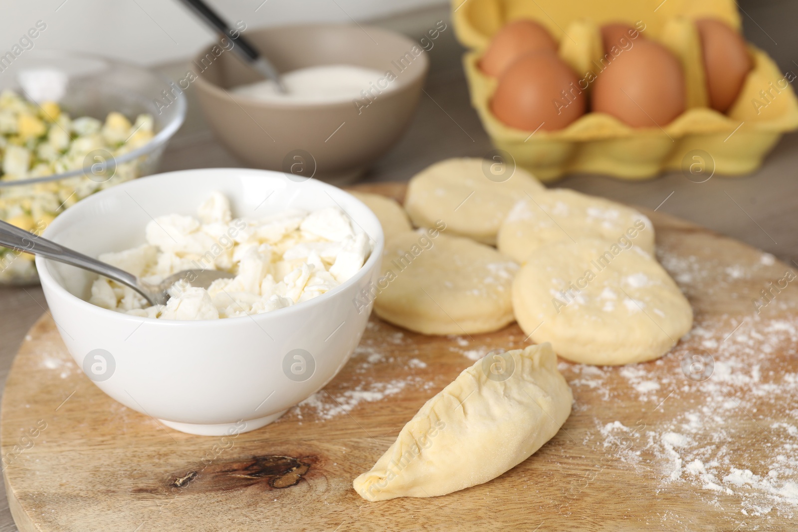 Photo of Making pirozhki (stuffed pastry pies). Pieces of dough with cottage cheese on table, closeup