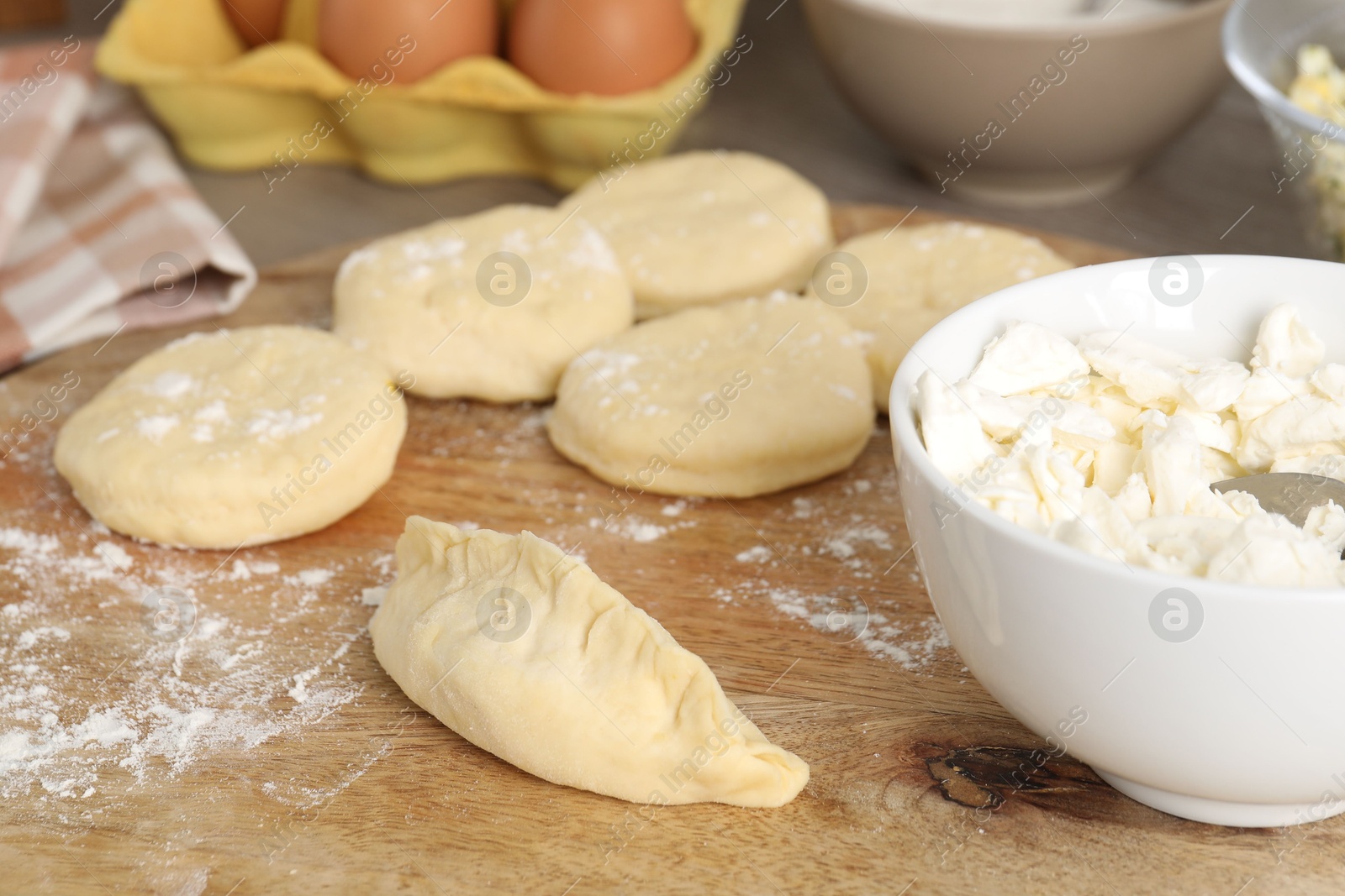 Photo of Making pirozhki (stuffed pastry pies). Pieces of dough with cottage cheese on table, closeup