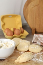 Photo of Making pirozhki (stuffed pastry pies). Pieces of dough with cottage cheese on table, closeup