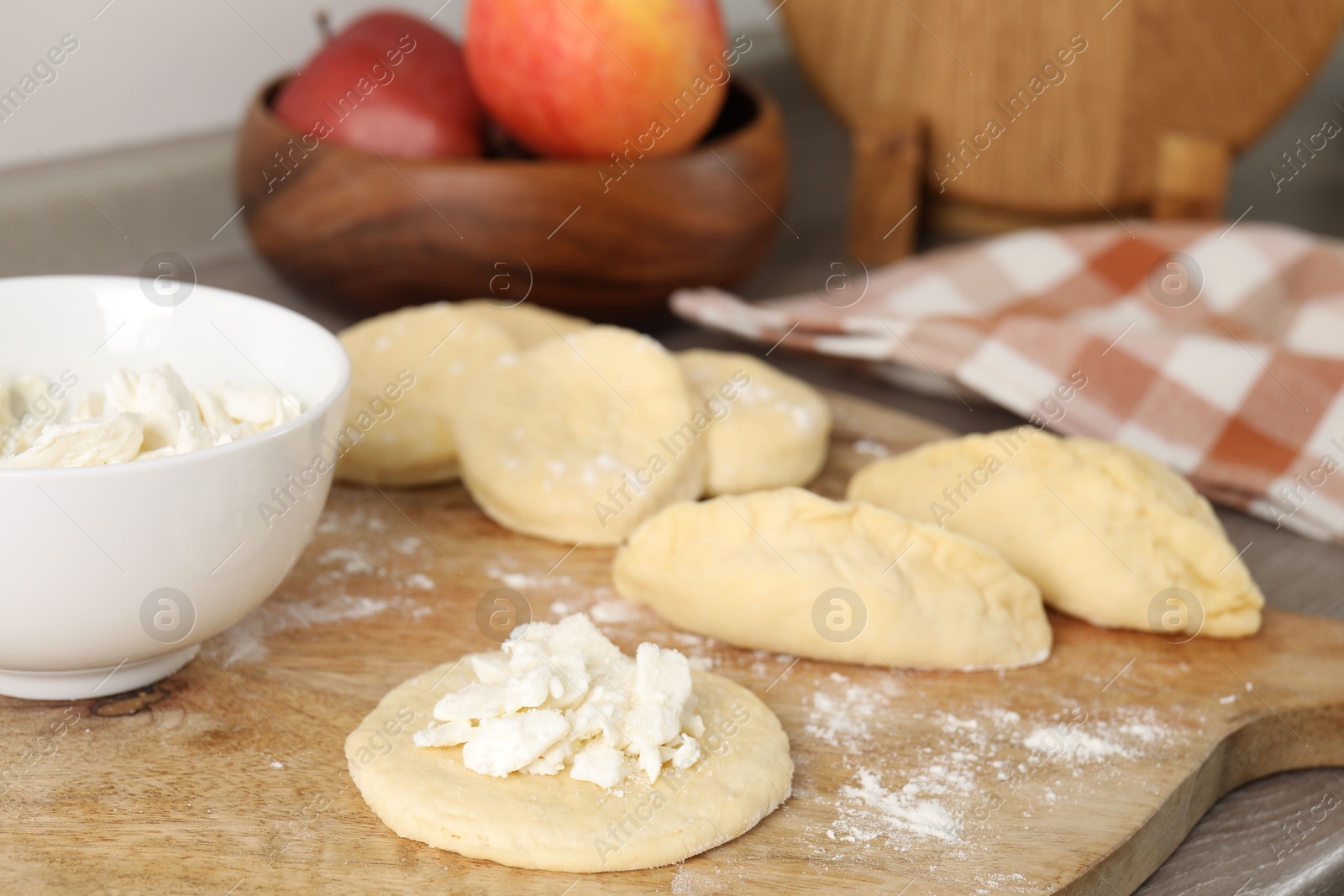 Photo of Making pirozhki (stuffed pastry pies). Pieces of dough with cottage cheese on table, closeup