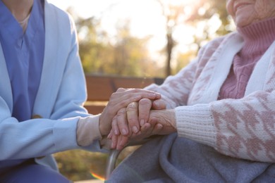 Photo of Caregiver with elderly woman in park, closeup