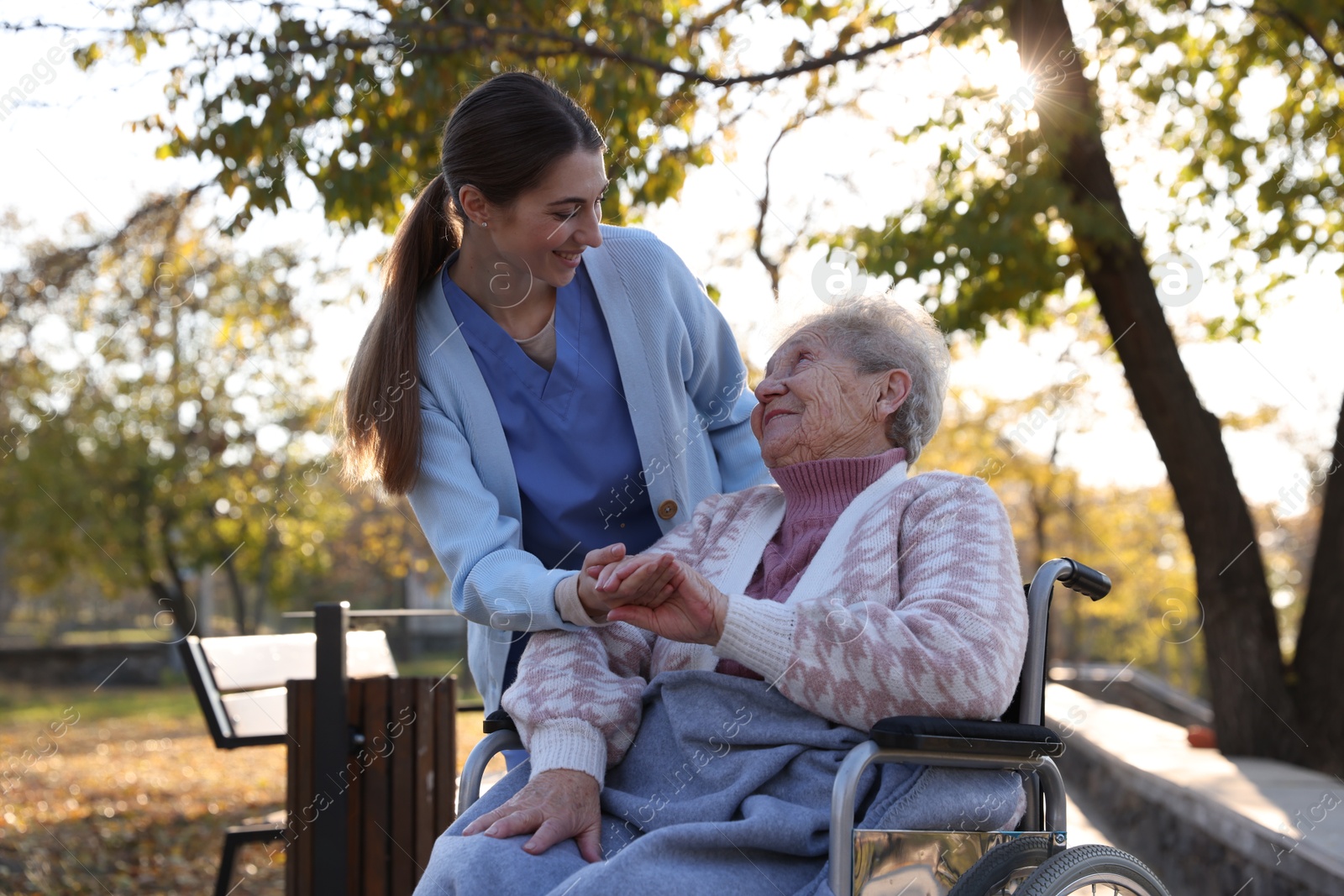 Photo of Caregiver with elderly woman in wheelchair at park