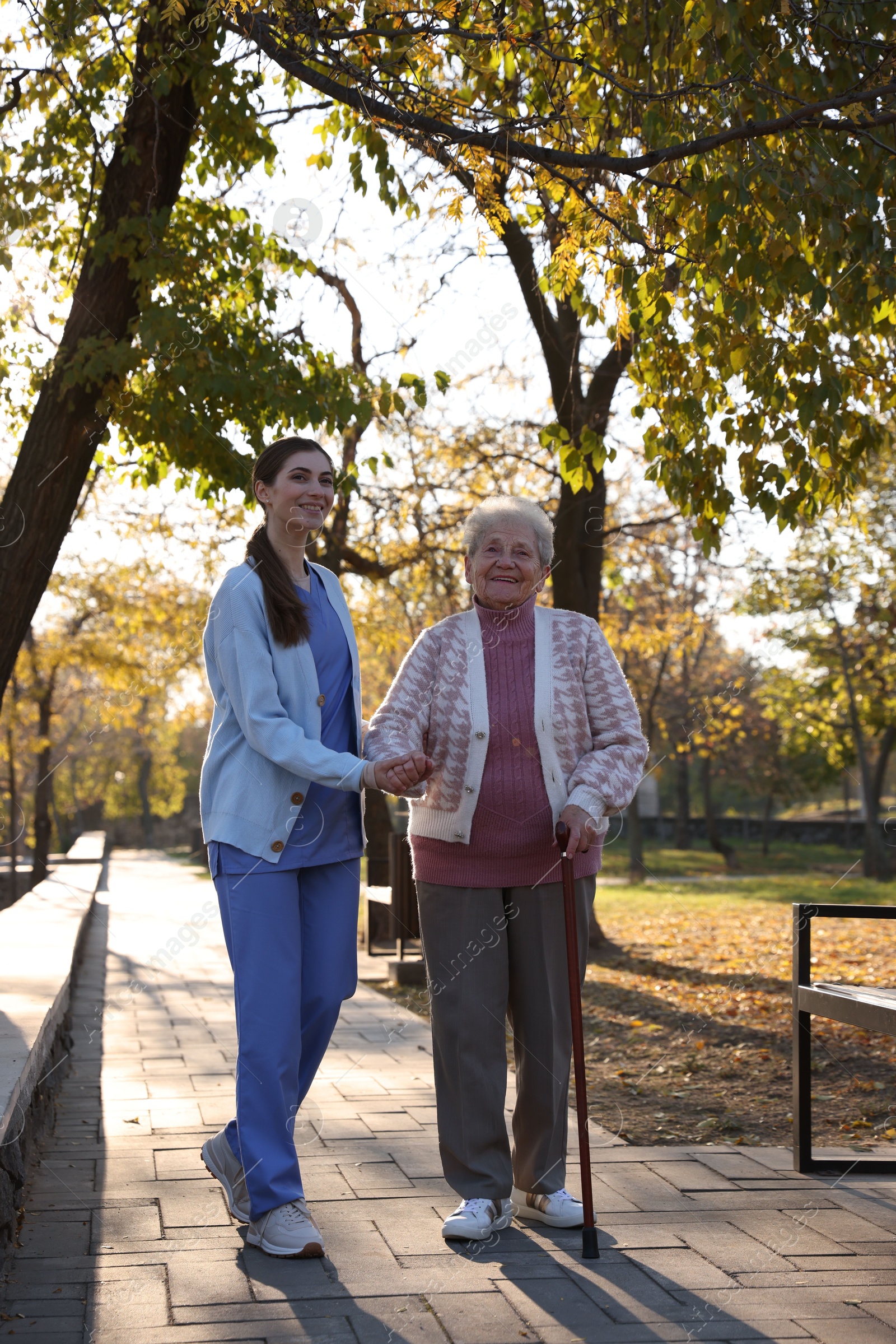 Photo of Elderly woman with walking cane and her caregiver in park