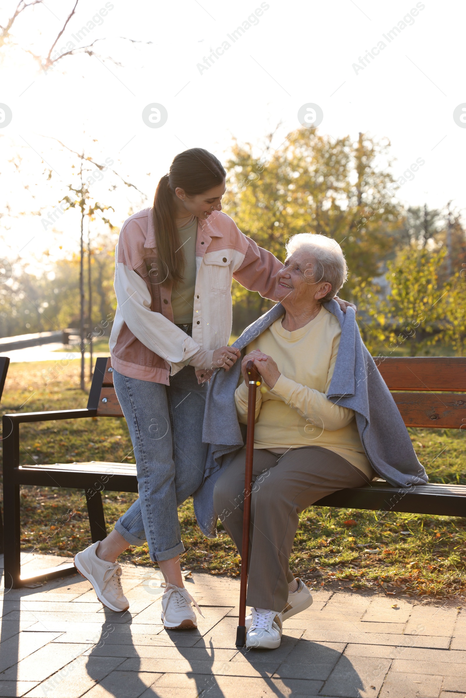 Photo of Elderly woman with walking cane and her caregiver in park