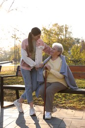 Photo of Elderly woman with walking cane and her caregiver in park