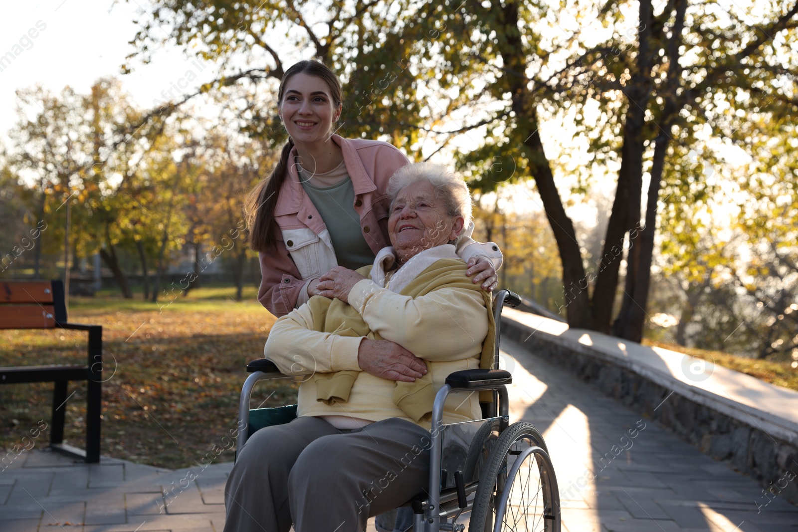 Photo of Caregiver with elderly woman in wheelchair at park